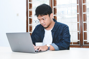 Fototapeta premium Young Asian man feeling serious when work laptop on table.