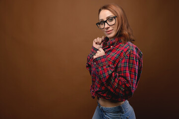 Portrait of a young attractive Caucasian woman in a red shirt and glasses on a brown background. Advertising glasses for improving vision and optics salons