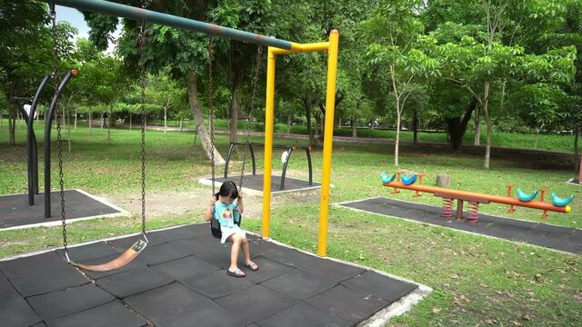 Lonely kid play swing in playground. Lonely, boring concept