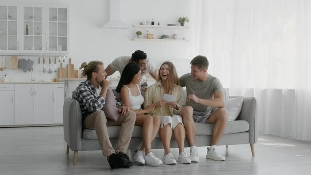 Happy young woman sharing pregnancy news with group of friends at home