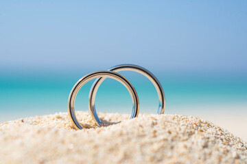 Pair wedding rings in sand on tropical beach