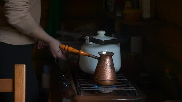 Woman is preparing Turkish coffee in copper cezve at home. UHD video