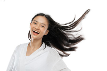 smiling girl wearing a towel is standing with her long hair blowing by wind on gray background