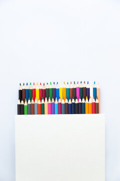 Set of colored watercolor pencils in a box isolated on a white background. View from above.