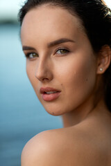 Naklejka premium Portrait of a beautiful woman with wet hair against the backdrop of the sea and sunset. fashionable stylish young woman on tropical beach