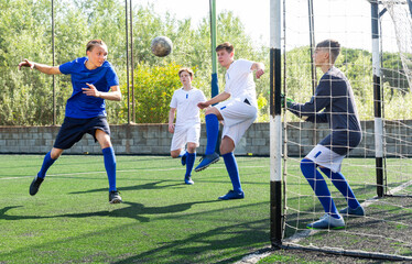 Youthful football players challenging for ball in goalmouth zone