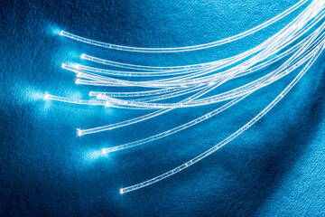 Bundle of optical fibers with lights in the ends. Blue background.