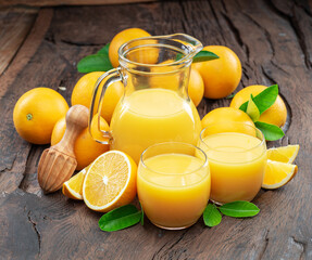 Yellow orange fruits and fresh orange juice isolated on dark wooden background.