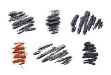 A scattering of eyeshadows of charcoal gray and golden sand colors, piles isolated on white...