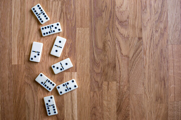 White dominoes on the wooden background, top view. Table game. Place for text