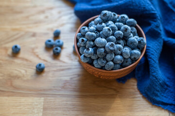 Blueberries in clay bowl on a wooden background