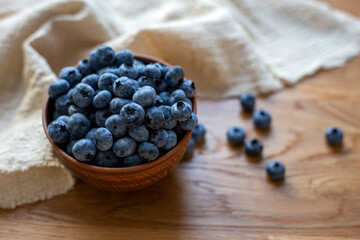 Blueberries in clay bowl on a wooden table, close up