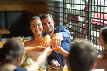 Happy just married couple showing rings to friends during party in the restaurant