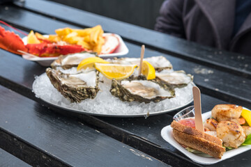 Oyster with Lemon, bread, lobster with chips serve on plate.