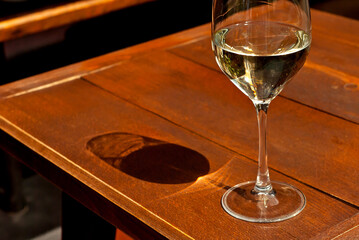 Glass of white wine close up. Alcoholic drink on a wooden table on a background of the city. Transparent wine on the summer terrace of the restaurant.