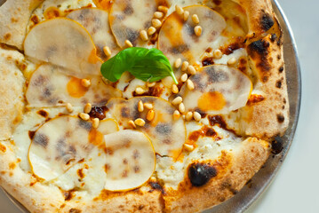Pizza on a metal plate close up. Pizza with cheese, pear and pine nuts.