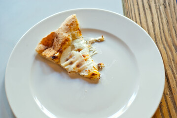 Triangular slice of pizza on a white plate close up. Pizza with cheese, pear and pine nuts.