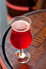Glass of red wine close up. Alcoholic liqueur on a wooden barrel.