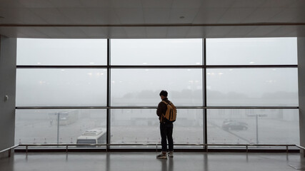 Fototapeta na wymiar A man standing in front of big window at Shanghai Pudong International Airport.