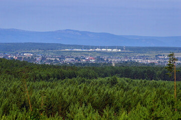 Fototapeta na wymiar Panoramic view of the small town in Russia, Eastern Siberia. There is a dense green pine forest around it. Summer landscape