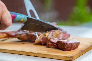A man cuts cooked fried meat on a cutting board. Oven-baked meat for dinner.