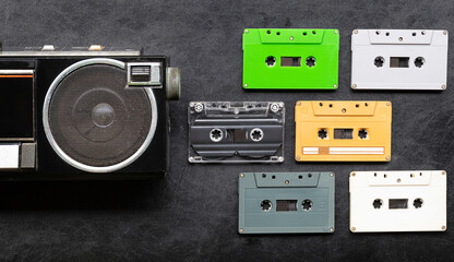 Top view half retro radio and colorful cassette tape on black floor with copy space