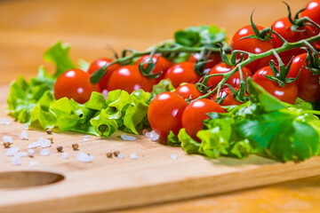 Fresh cherry tomatoes with green salad and garlic on a cutting board. Healthy food concept. Vegetarianism.