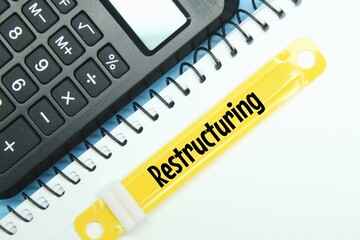 paper binder, white paper, calculator with the word restructuring