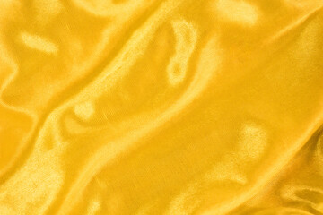 Golden silk or satin texture. Smooth elegant and luxury fabric background with copy space. Golding liquid