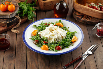 Burrata cheese arugula salad on a rustic wooden background