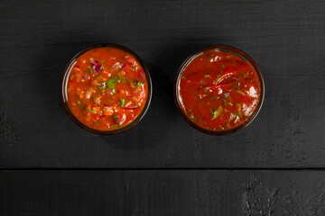 Tomato sauces in glass dipping bowls on black wooden background