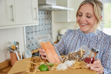 Woman Unpacking Online Meal Food Recipe Kit Delivered To Home