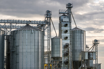Modern Granary elevator and seed cleaning line. Silver silos on agro-processing and manufacturing plant for storage and processing drying cleaning of agricultural products, flour, cereals and grain.