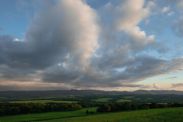 Naklejka premium beautiful clouds at sunset green meadow