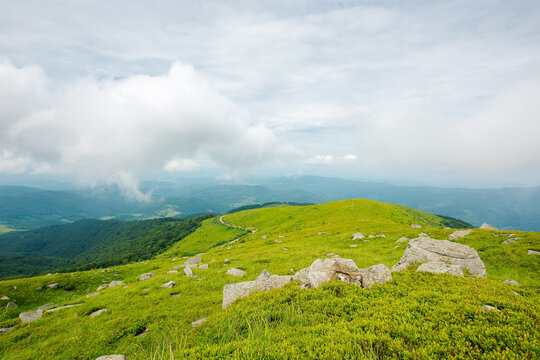 green nature landscape. beautiful summer scenery in mountains. stones on the grassy hills rolling in to the distant ridge beneath a cloudy sky