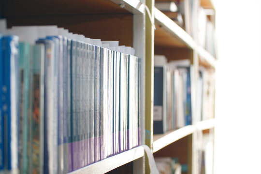 Books on a shelf in the library on a light background. Selective focus