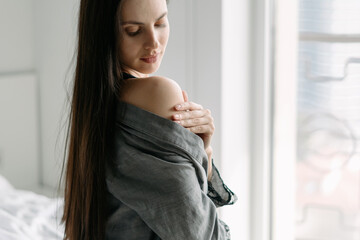 Young woman touching her naked shoulder at home