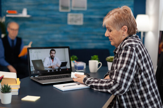 Senior Patient Looking At Pills Bottle While Listening Diagnnos. Elderly Woman On Telemedicine Online Conference Call With Practitioner Doctor Using Modern Healthcare Technology, Web Diagnosis