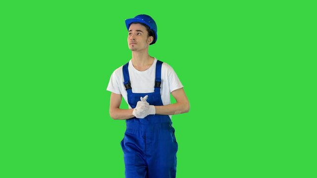 Confident young male builder walking looking to the sides on a Green Screen, Chroma Key.