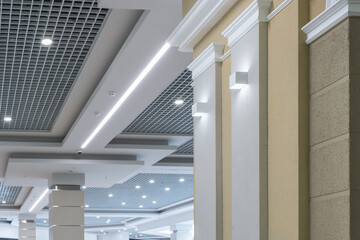 suspended and grid ceiling with halogen spots lamps and drywall construction in empty room in store...