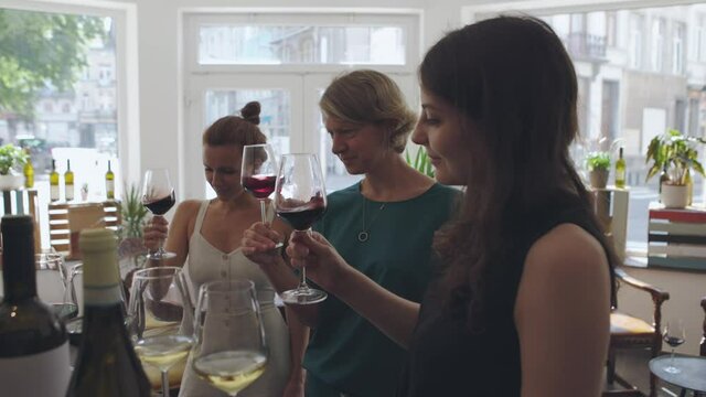 three women drinking in a wine tasting - people proving wine in the wine shop - wine presentation and social gathering