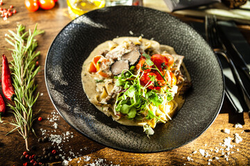 Black Angus beef tagliatelle pasta with fresh black truffles and parmegano. Delicious healthy traditional food closeup served for lunch in modern gourmet cuisine restaurant