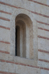 Fototapeta na wymiar A close-up of a simple but stylish stone arched window set in the side of an Italian building