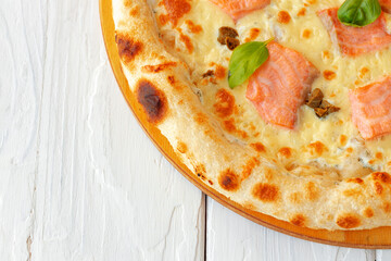 Pizza with baked salmon on wooden table