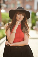 Fashion outdoors portrait of an elegant model girl with bright makeup in trendy hat on a summer sunny day