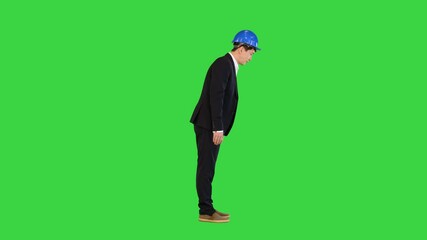 Bowing young asian engineer in a helmet and a suit on a Green Screen, Chroma Key.