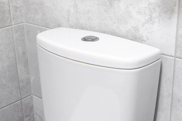 Toilet tank cistern of white ceramic toilet in modern bathroom interior with marble tile
