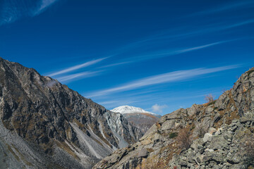 Colorful alpine landscape with great mountain in autumn colors with snow on peak under cirrus...