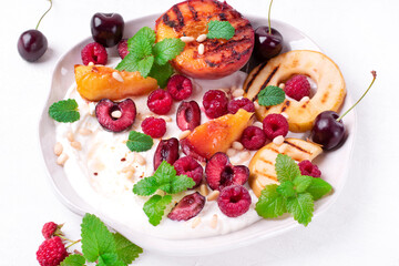 Grilled peach and apple in cottage cheese cream topped with raspberry, cherry, mint and pine nuts. Served summer dessert