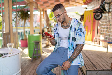 Chico con camisa de flores tatuado en bar de verano